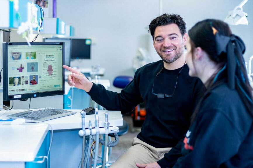 Dr. Jason Priestly of Cali Kids Dental with dental assistant reviewing info on computer screen.