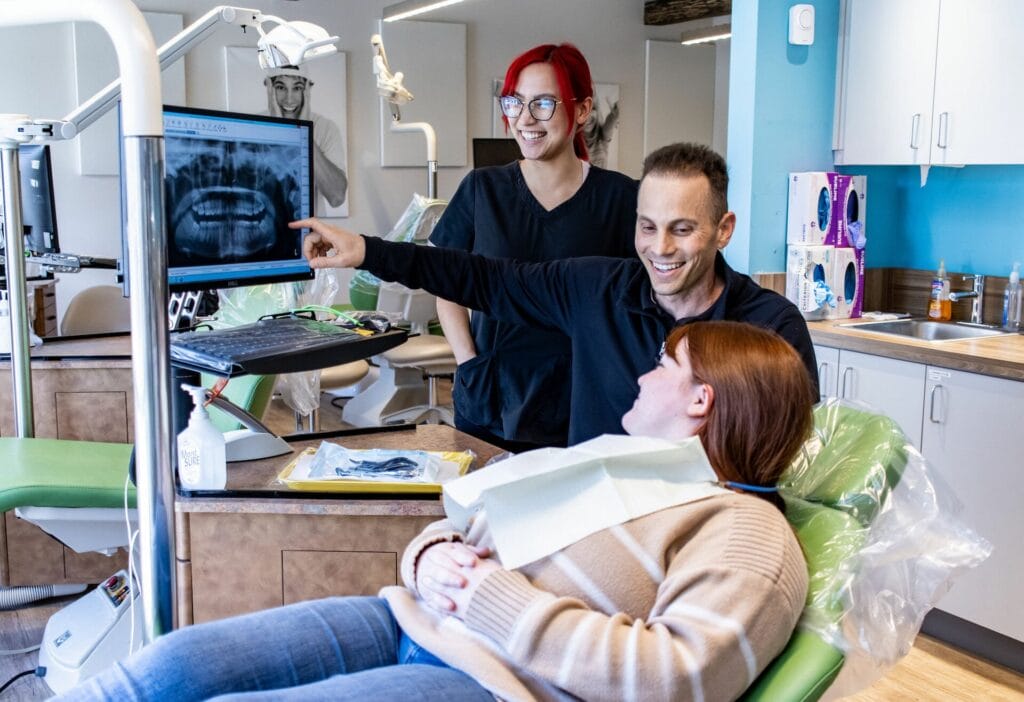 Dr. Paolo Poidmore of Poidmore Orthodontics and Precision Orthodontics with dental assistant and patient reviewing case on computer screen on Clinical Resources page